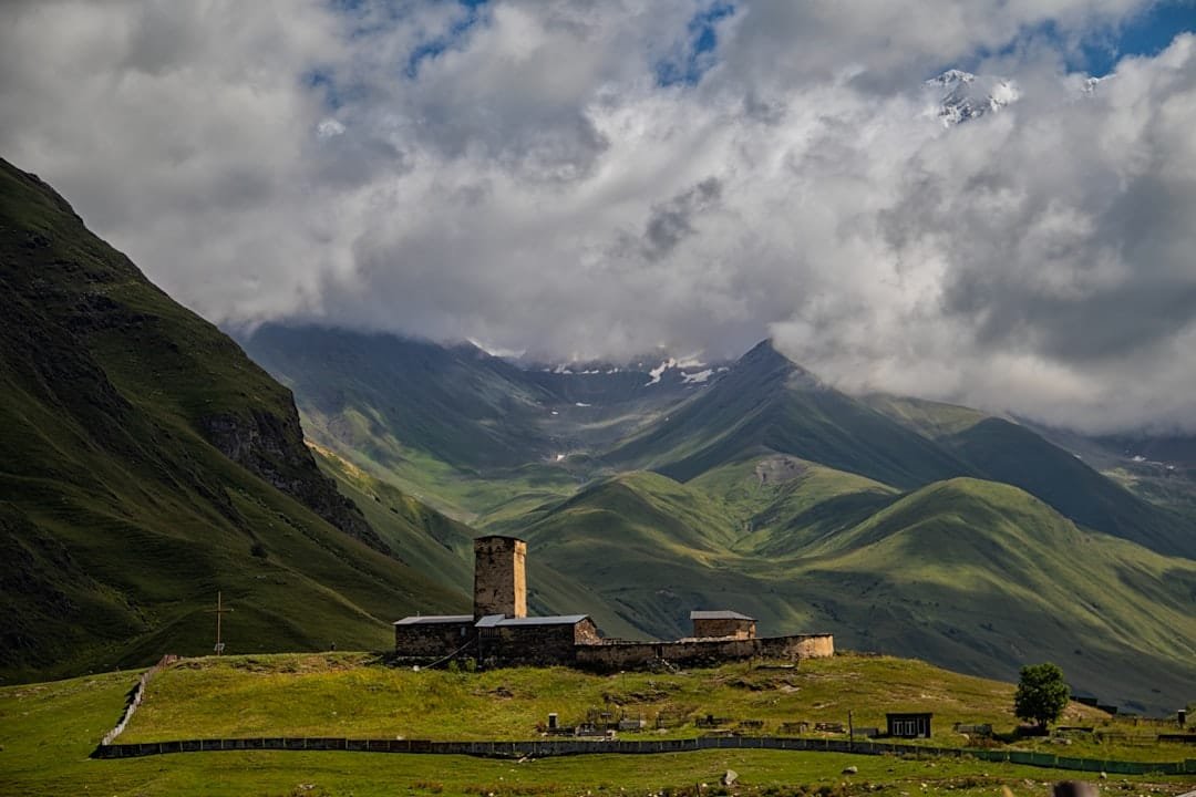 A farm in the mountains under a cloudy sky
